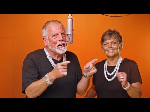 A grey-bearded grandpa and a grandma in pearls rapping in the orange booth